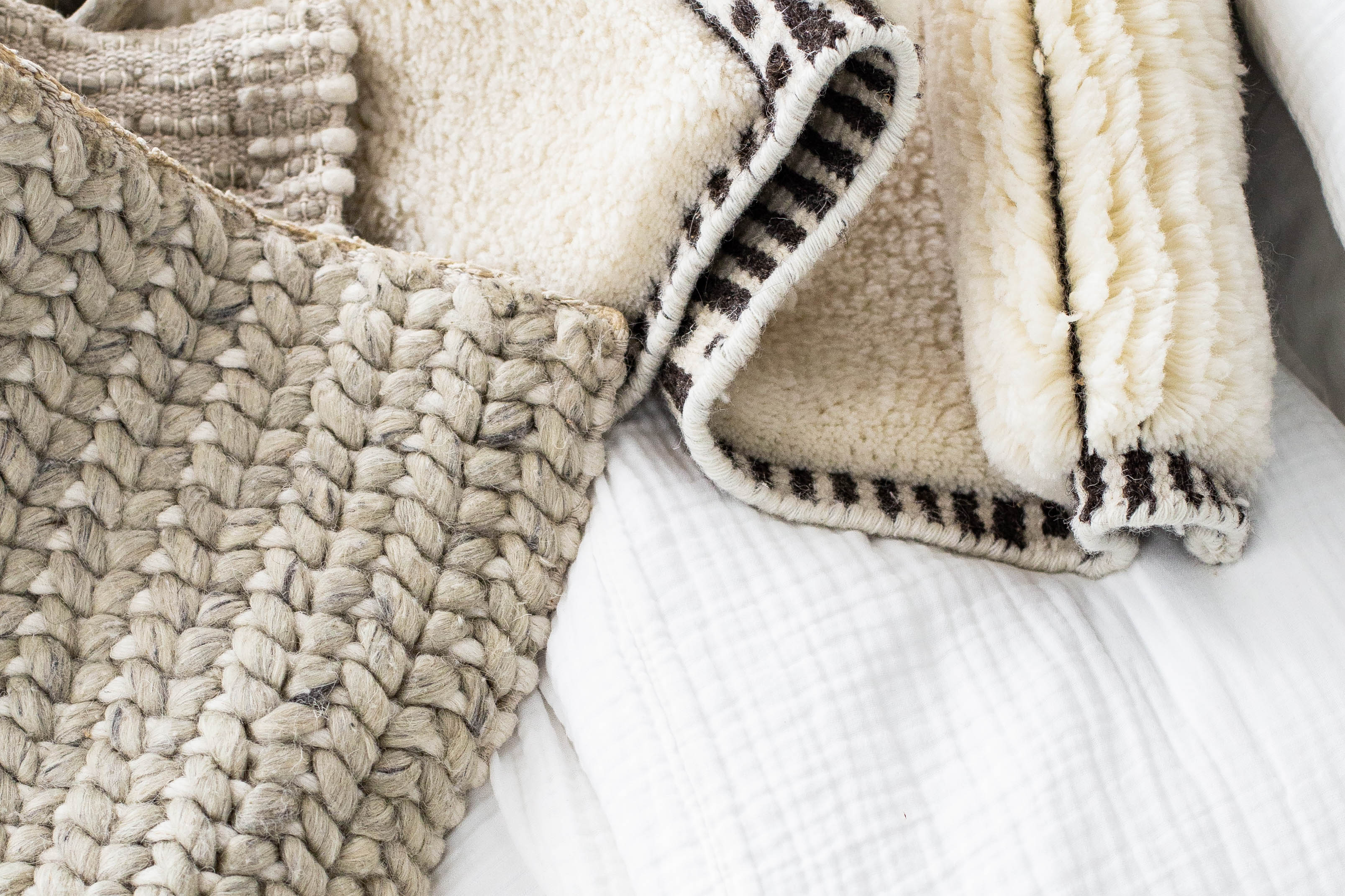 Various neutral coloured rugs in a pile. Created by rug design studio, Studio321B, in Toronto, Ontario.