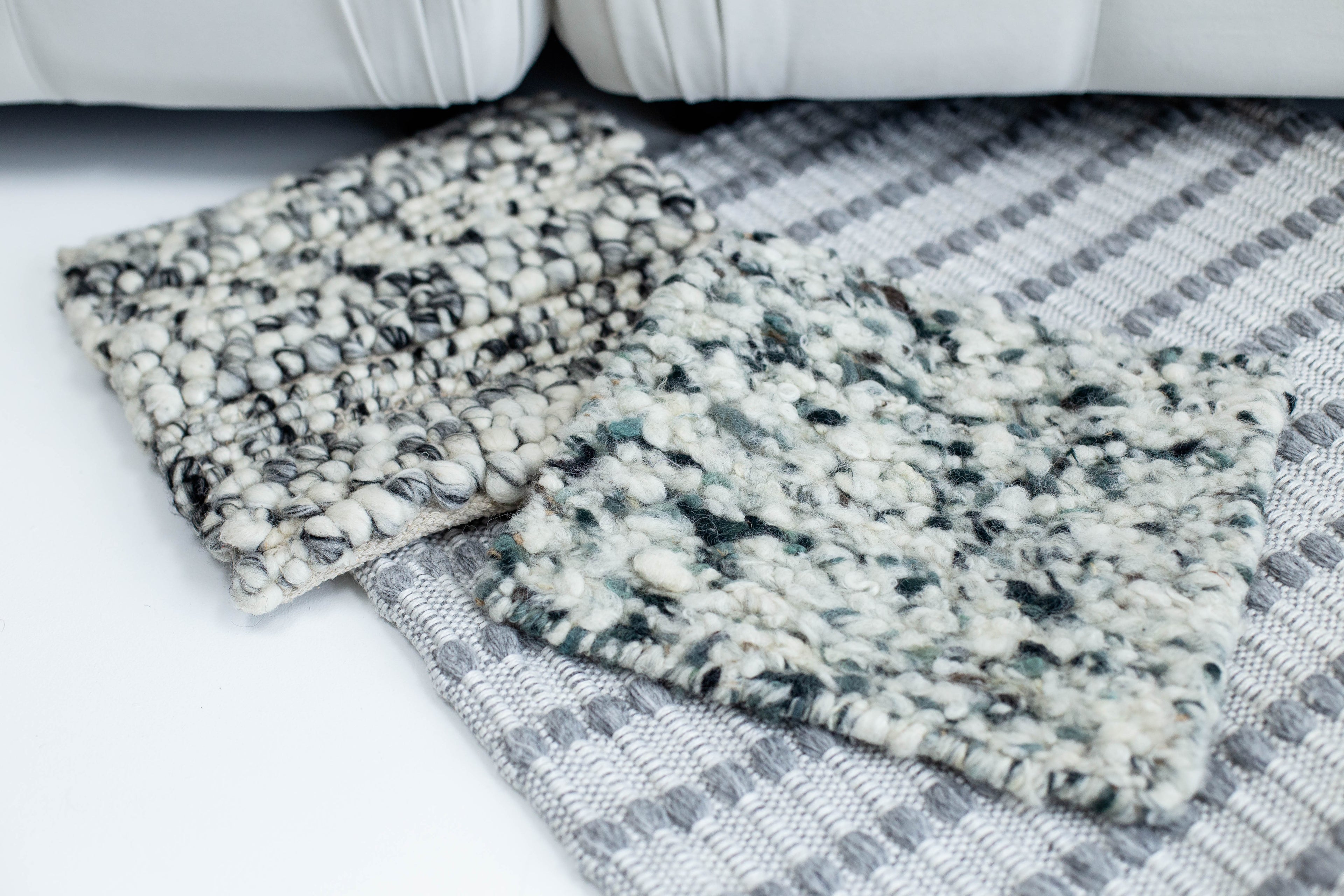 Layered wool area rugs with grey pattern detail, styled in a modern interior showcasing contemporary carpet design and natural fibres.
