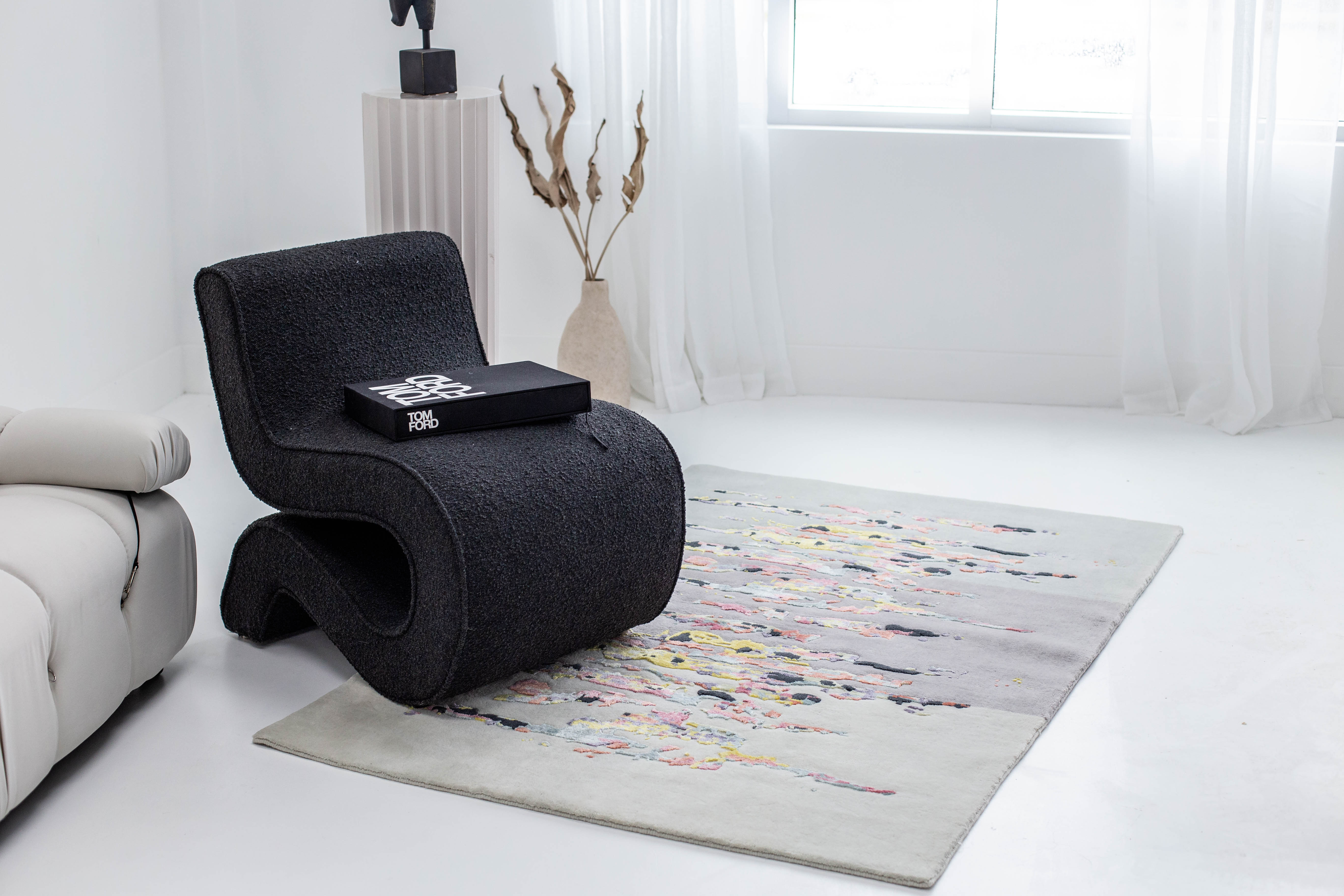Multicolor carpet in white interior. Black, modern style chair on top of rug. Rug created by Studio 321B, Toronto.