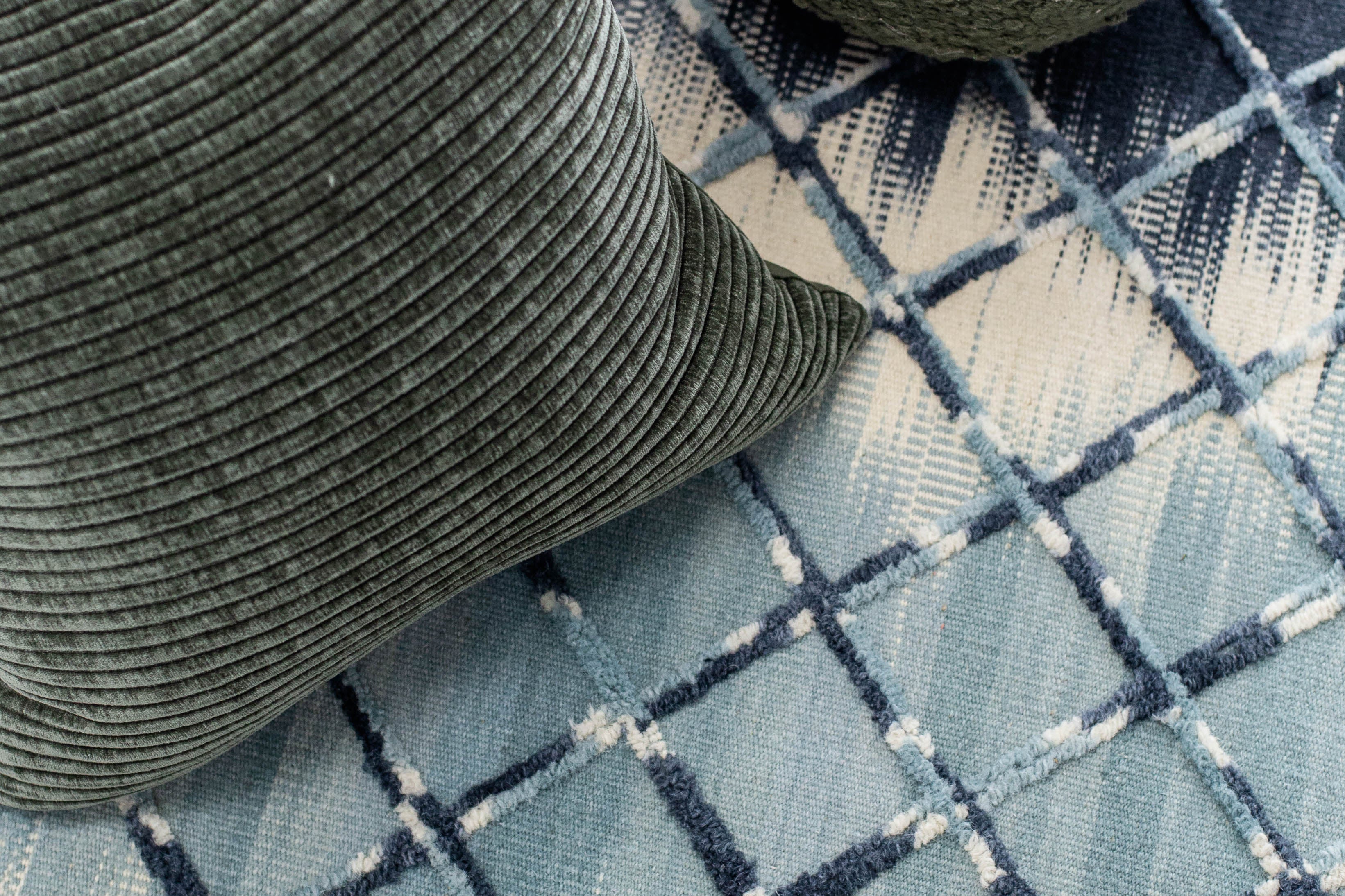 Toronto wool rug with blue geometric pattern styled with green accent pillows in a modern living space