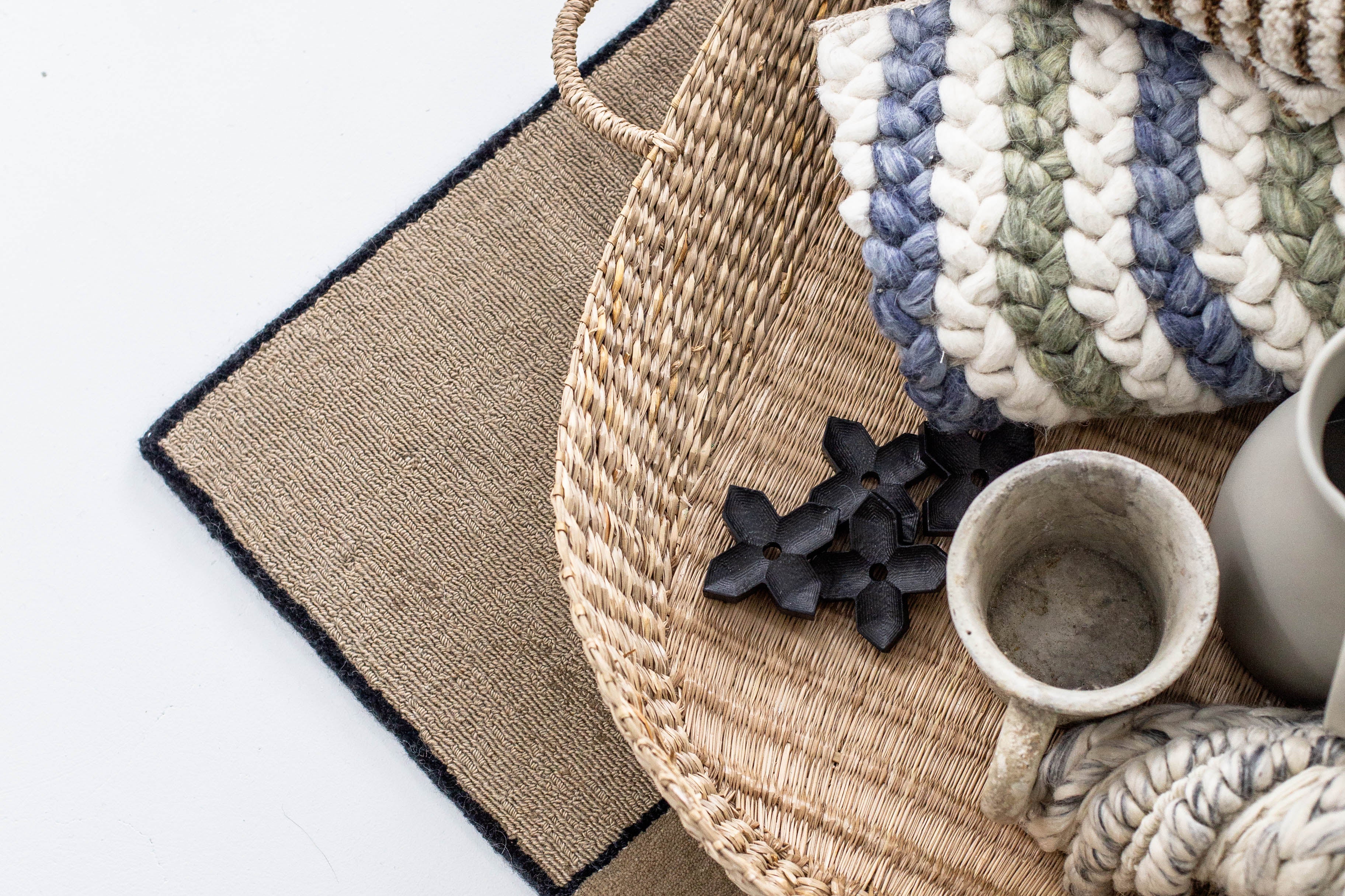 Layered neutral area rugs with black border detail, styled in a modern interior. Contemporary carpet design created by Studio321B.