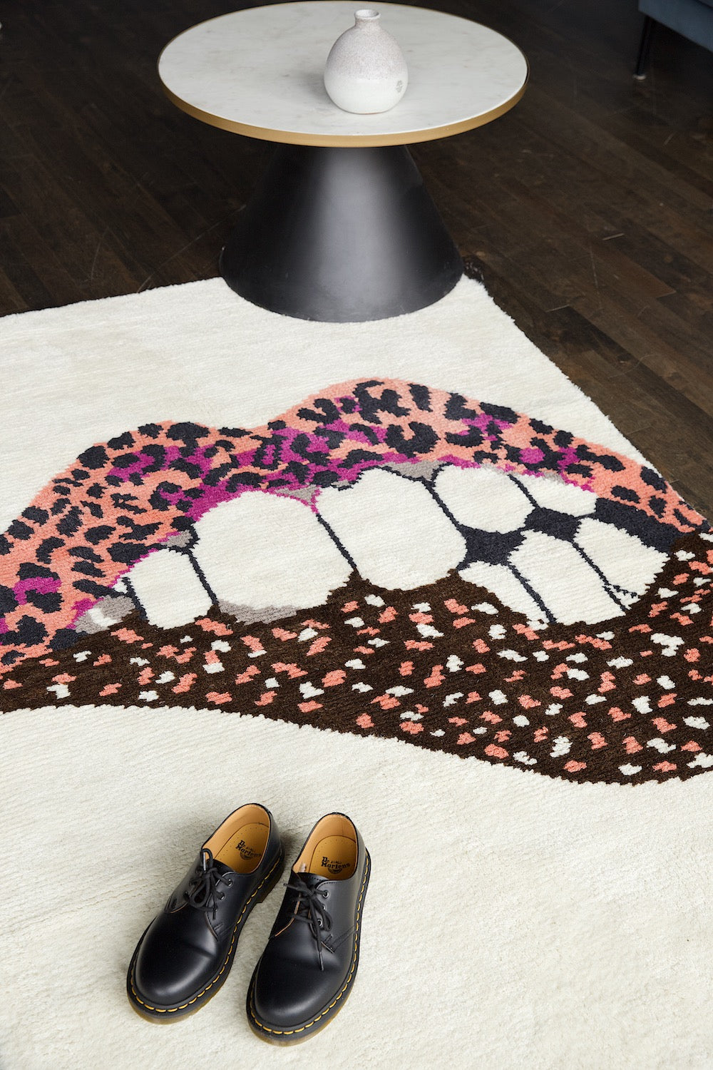 Rug with lip-shaped, leopard print design, with black shoes in front.
