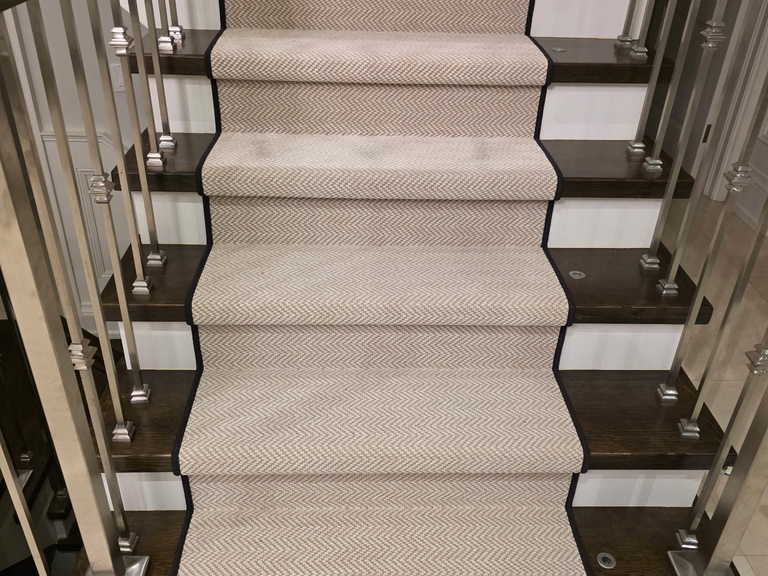 Staircase with a patterned carpet runner in a well-lit interior setting. Toronto Carpet Installation by Studio321B.
