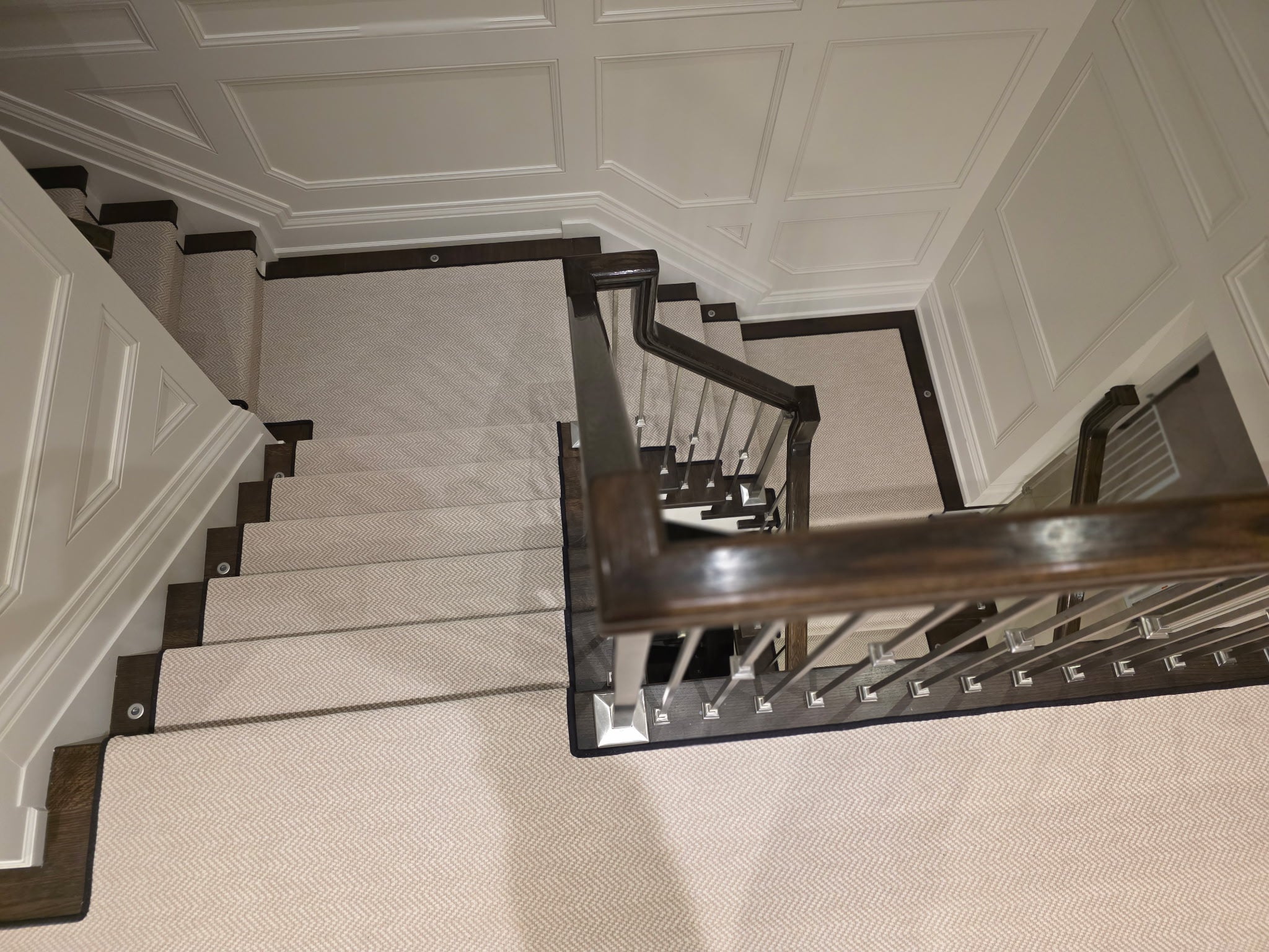 Staircase rug runner installation. Installed by Toronto carpet store, Studio321B. White carpet on dark hardwood stairs.