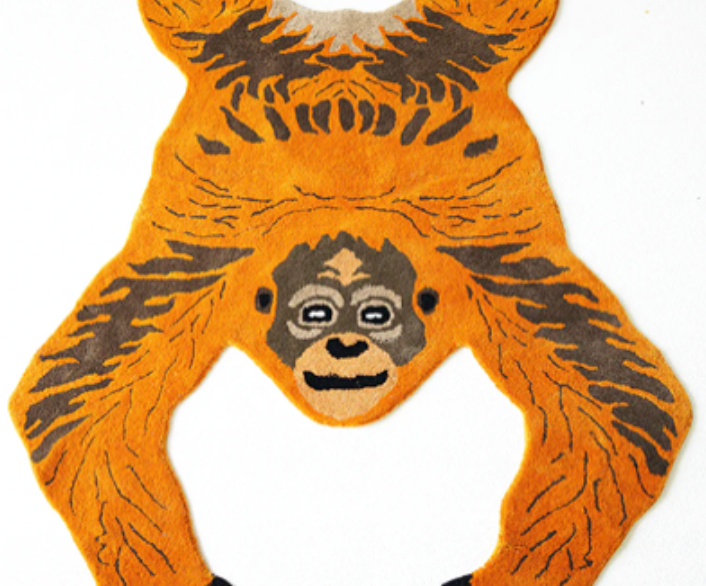Monkey-shaped rug with orange and black design on a white background