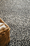 Black and white plush wool rug by Studio 321B. Small brown wicked baskets on top of the rug.